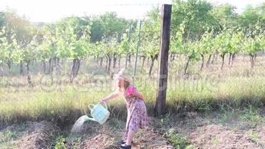 小女孩穿花裙和白帽子。 小女孩给花园浇水
